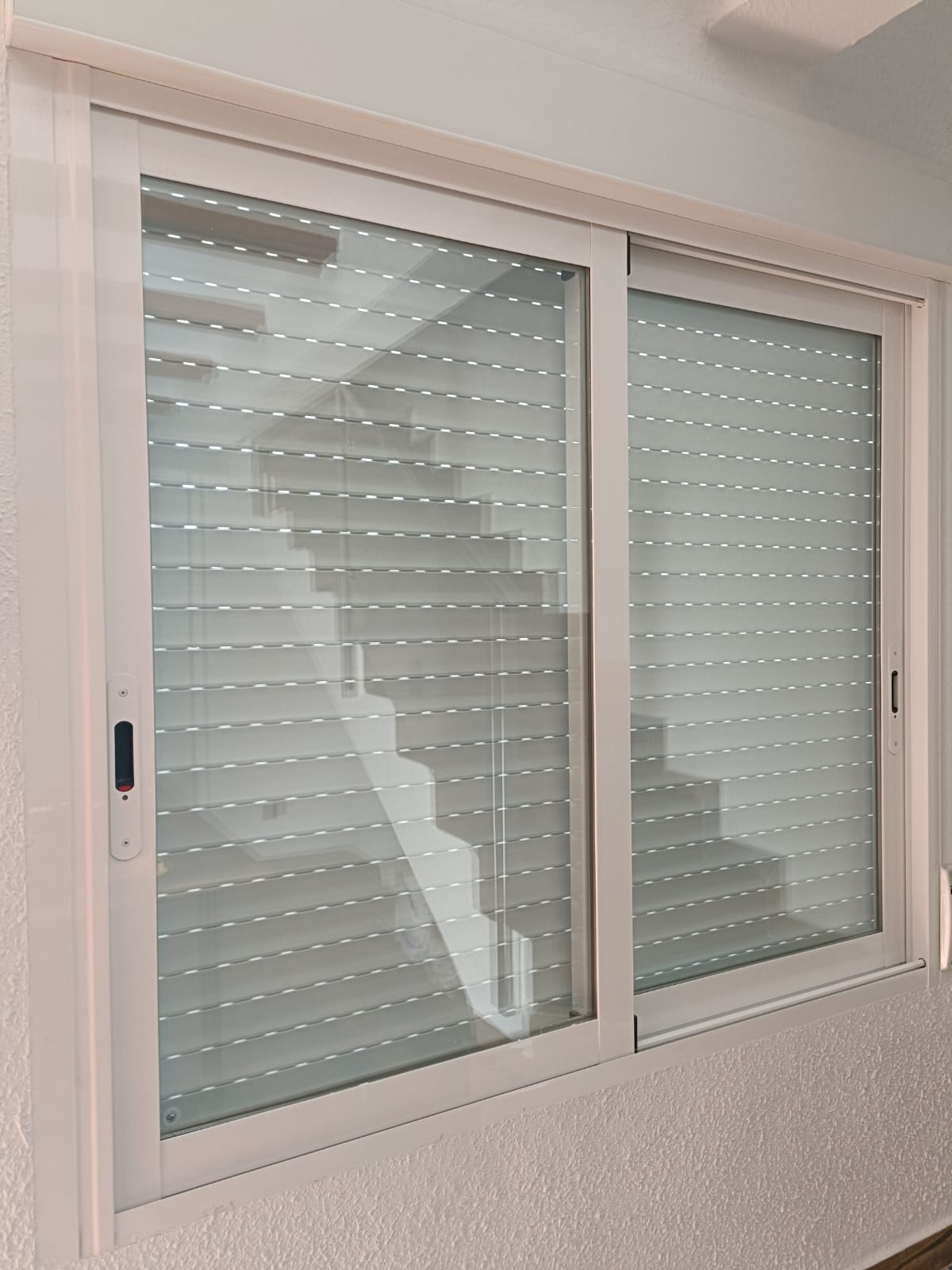 Ventana corredera blanca con persiana instalada